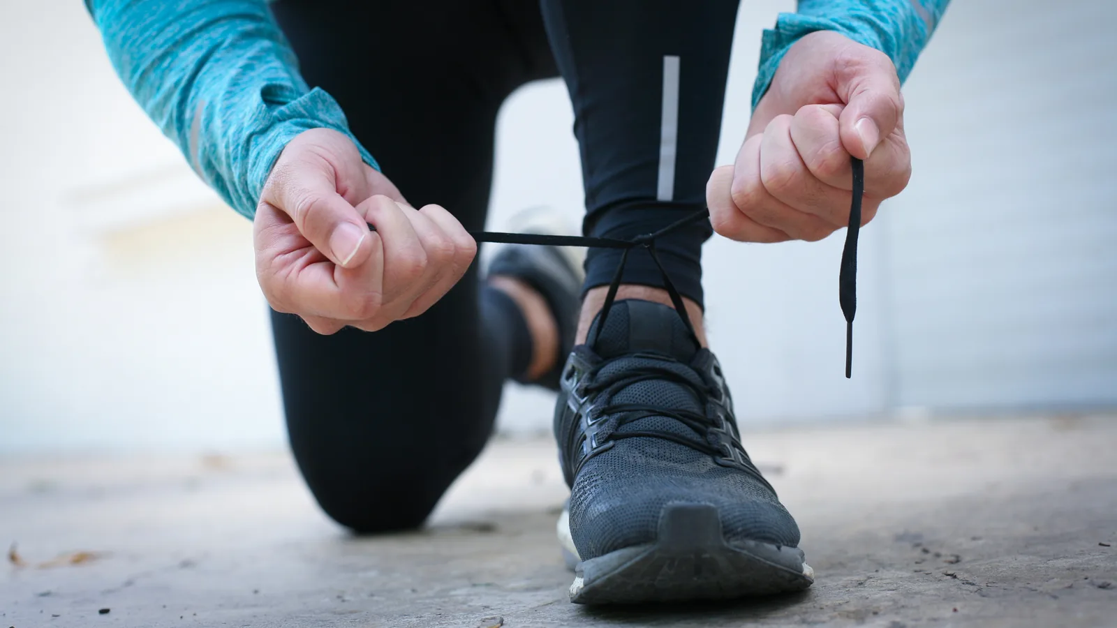 Someone kneeling down to tie their trainer laces before a session